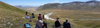 Vista di una valle montana con escursionisti che contemplano il paesaggio.